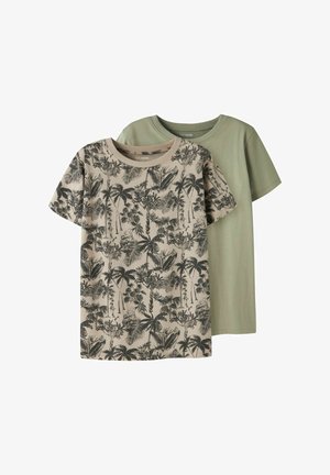 To kortærmede t-shirts, den ene ensfarvet olivengrøn og den anden beige med sort tropisk palmebladprint, lagt ovenpå hinanden på hvid baggrund.