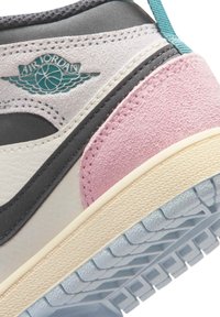 Prim-plan al unei adidași Air Jordan multicolori, cu logo teal, toc roz din piele întoarsă, talpă intermediară crem și talpă exterioară texturată albastru deschis.