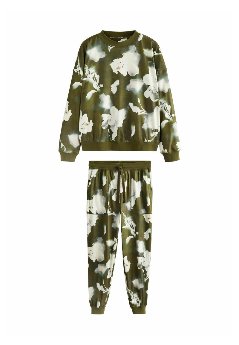 Zestaw oliwkowej zielonej bluzy i spodni dresowych z dużym białym i jasnoszarym nadrukiem kwiatowym oraz ściągaczami przy mankietach i w pasie.
