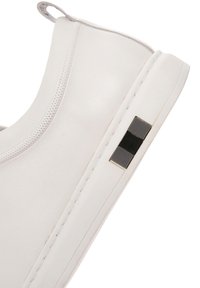 Sneaker bianco in pelle con design perforato e un accento rettangolare nero sul lato. Presenta una punta rotonda e una suola piatta in gomma.