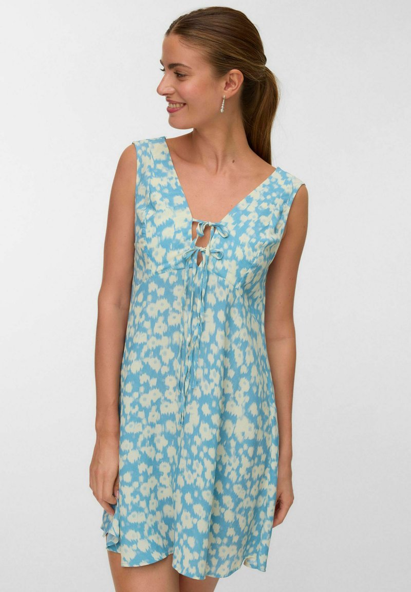 Hellblaues ärmelloses Kleid mit tiefem Ausschnitt, das an der Vorderseite einen Kordelzug besitzt und mit einem Blumenmuster in Blau- und Cremetönen verziert ist.