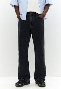 Jeans in denim nero con una vestibilità rilassata, caratterizzati da un classico design a cinque tasche e una texture leggermente sbiadita. Abbinati a sneakers nere.