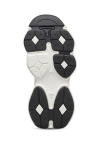 Suola di una sneaker caratterizzata da una combinazione di colori bianco e nero, con gomma testurizzata, motivi di trazione esagonali e a diamante, e dettagli in rilievo.