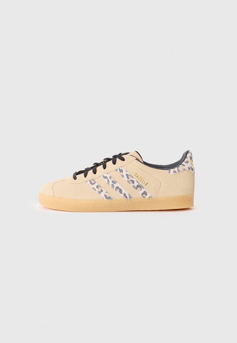 Baskets en daim beige avec lacets noirs, présentant trois rayures imprimées léopard et une semelle en caoutchouc texturée. Marquage sur le côté.