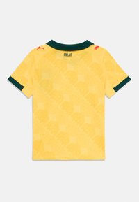 Gul kortermet sportstrøye med mørkegrønn krage og kant på ermene, subtilt mønster, "MILAN" tekst under kragen, og røde Puma-logoer på skuldrene.