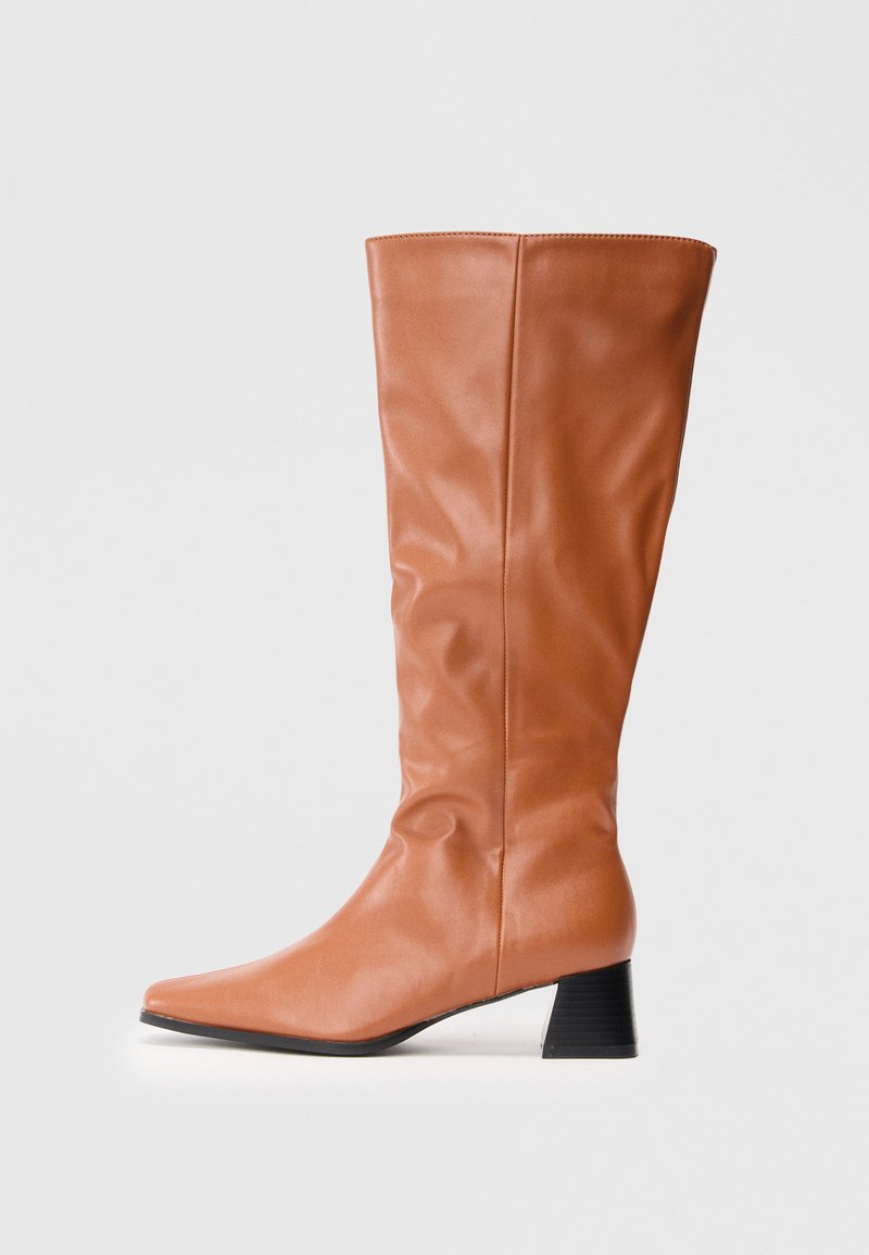 Tall brown leather boot with a low black block heel and slightly pointed toe, shown from side on white background.
