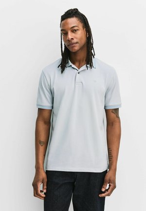 Lyseblå polo med glat stof, der har en to-knaps slids, korte ærmer med blåstribede manchetter og en diskret logo.