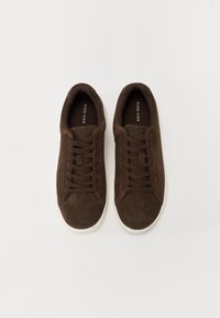 Brown suede sneakers with round toes, white rubber soles, and brown laces. Interior features a branded label. Smooth texture throughout.