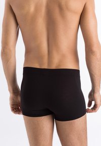 Black cotton boxer briefs with a smooth texture, a fitted design, and a soft elastic waistband. The back view shows the cut and fit.