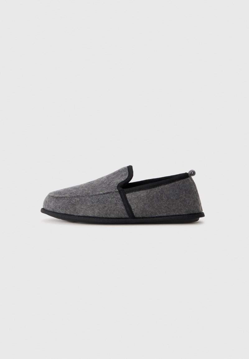 Graue Hausschuhe mit runder Form, schwarzem Rand und einer kleinen Schlaufe hinten. Weiche Textur und einfaches Slip-On-Design.