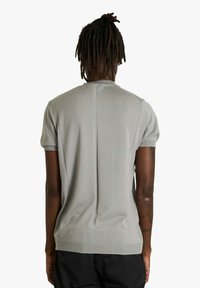 Maglione in maglia grigio chiaro a maniche corte con finitura testurizzata, caratterizzato da una cucitura centrale sulla schiena e orlo e polsini a coste.