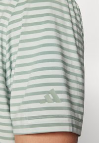 Ριγέ κοντομάνικο πουκάμισο σε φωτεινό πράσινο και λευκό, με απαλή υφή και διαφανή λογότυπο στο αριστερό μανίκι.