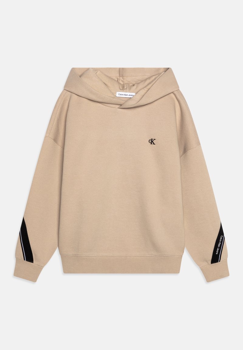 Sudadera beige con capucha, rayas negras y blancas en los brazos, pequeño logo "cK" en el pecho y texto "Calvin Klein Jeans" en el detalle de la manga.