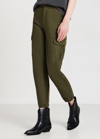 Olivgrüne Cargo-Hosen mit elastischen Bündchen, ausgestattet mit zwei Seitentaschen, kombiniert mit schwarzen Ankle-Boots aus glattem Leder.