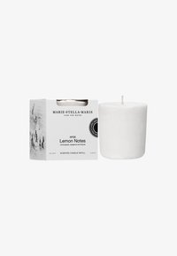 Duftlys genopfyldning i et cylindrisk design af hvid voks ved siden af en hvid boks mærket "Lemon Notes" med tekst og et sort-hvidt billede.