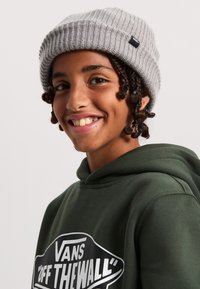 Grå ribbad mössa med en svart Vans-logotag, buren med en mörkgrön hoodies som har en stor vit "VANS OFF THE WALL" grafik.