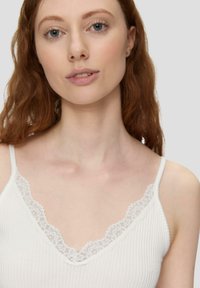 Biały ribbed tank top z dekoltem w serek, ozdobiony delikatną koronką na brzegach. Gładka tekstura, regulowane cienkie ramiączka.