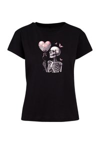 Black cotton t-shirt featuring a skeleton holding a pink heart-shaped balloon with lace details and butterflies. Short sleeves, classic fit.