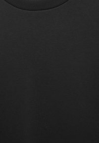 Krupan plan glatke crne tkanine s okruglim rebrastim izrezom na vratu, prikazujući teksturu i detalje pletenja.