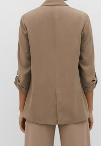 Bruine op maat gemaakte blazer met opgerolde mouwen, gladde textuur, enkele achterkantsplit en minimalistisch ontwerp. Getailleerd silhouet.