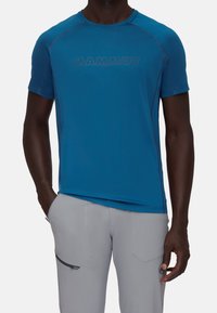 Blå, kortärmad teknisk skjorta med "MAMMUT"-logotyp i en mörkare nyans och raglanärmar. Slät tyg med en lätt lyster och stretch.