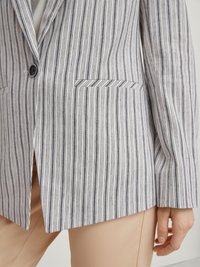 Striped blazer in white and navy, features a single button, notch lapels, two front pockets, and a relaxed fit with a vented hem.