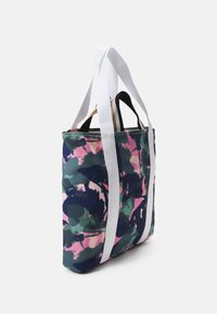 Sac en toile avec un motif abstrait multicolore dans des tons de vert, rose et bleu marine, doté de anses blanches et marron pour un transport facile.