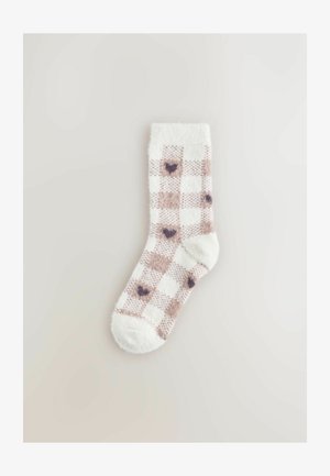 Plyšové kotníkové ponožky bílé barvy s hnědým kostkovaným vzorem, které obsahují malé tmavé srdce. Měkká textura se jednobarevným lemem.
