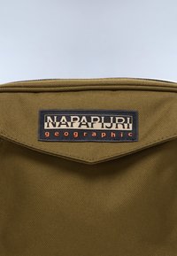 Τσάντα από υφασμάτινο ύφασμα σε ελιά πράσινη απόχρωση με ένα μαύρο και μπεζ λογότυπο Napapijri Geographic στο εμπρόσθιο καπάκι της.