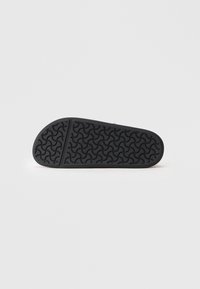 Sole di scarpa in gomma nera con un motivo a zigzag testurizzato e bordi arrotondati. La superficie è liscia con una leggera lucentezza.