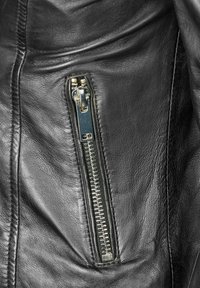 Schwarze Lederjacke mit einer seitlichen Reißverschlusstasche, die einen silbernen Metallreißverschluss und eine strukturierte Lederoberfläche aufweist.