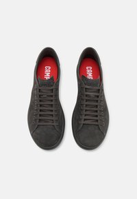 Baskets en daim noir avec une texture lisse, dotées de lacets gris, de semelles intérieures rouges et d'un logo imprimé sur la languette. Design à profil bas.