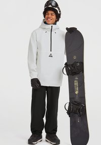 Witte waterdichte jas met een zwarte rits, gecombineerd met zwarte broek en handschoenen. Voorzien van een zwarte snowboard met grafische ontwerpen en bindingen.