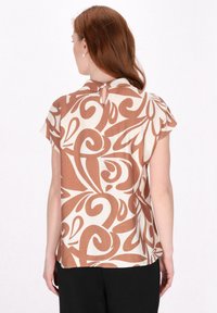 Bluse in braun-creme Muster, mit kurzen Ärmeln, einem Schlitzverschluss im Rücken und einer weichen Textur, aus leichtem Stoff gefertigt.
