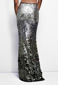 Jupe en sequins argentés au design ajusté, longue jusqu'au sol, avec un subtil éclat provenant de sequins ronds superposés. Détail de ceinture noire.