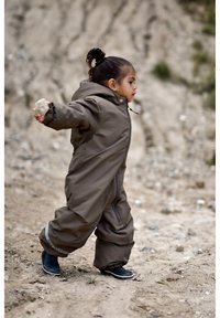 Brown waterproof overall suit with a hood, featuring a front zipper, elastic cuffs, and reflective accents, worn by a child holding a rock.