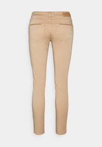 Beige slim-fit trousers with a soft texture, featuring a mid-rise waist, five-pocket design, and stitching detailing on the back pockets.