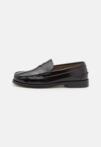 Mocassins en cuir noir avec un bout arrondi, des coutures sur le dessus, un talon bas et une finition lisse. Accents rouges sur le côté.