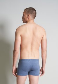 Blauwe sportboxers gemaakt van zachte stof, met een elastische tailleband en een gladde textuur. Model staat met de achterkant naar de camera.