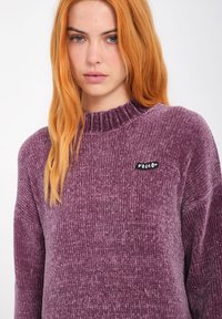 Lilla struktur sweater med en ribbet halskant. Har et lille sort "Volcom" logo patch på fronten. Blødt, hyggeligt materiale.