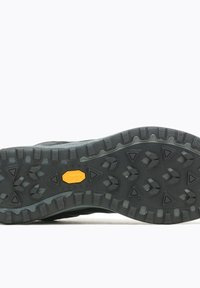 Suola di scarpa da hiking nera con tasselli profondi e robusti, caratterizzata da un logo Vibram giallo al centro. Gomma resistente con modelli di presa testurizzati.