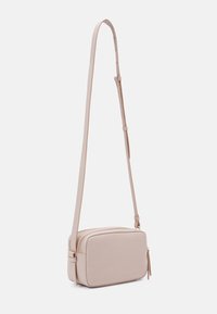 Light pink crossbody bag made of textured material, featuring a rectangular shape, gold hardware, and adjustable strap. Two zippered compartments.