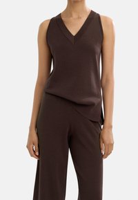 Brązowy bezrękawnik z dekoltem w serek, wykonany z miękkiego materiału, oluźnionym kroju i subtelnymi bocznymi rozcięciami dla dodatkowego wykończenia.