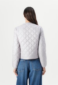 Quilted, light gray cropped jacket with a round neckline and long sleeves. Features a diamond pattern and soft, smooth texture.