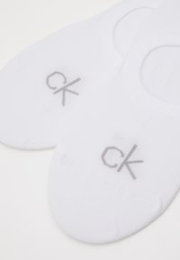 Valged madala lõikega sokid, mis on valmistatud puuvilla segust ja omavad siledat tekstuuri. Ülemisel poolel on hall "ck" logo. Ümar varba disain.