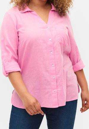 Lichtroze linnen overhemd met een V-hals en knoopsluiting. Opgerolde mouwen, een enkele borstzak en een gebogen zoomdetail.