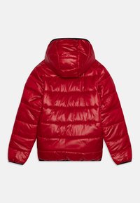 Punainen puhvelitakki, jossa on kiiltävä, tikattu pinta, huppu ja joustavat hihansuut. Sisältää vaakasaumaat ja sileän pinnan.