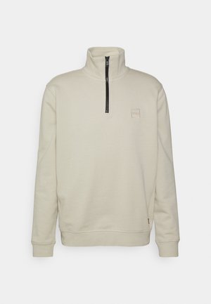 Lichtbeige pullover sweatshirt met een hoge kraag, halve rits aan de voorkant, en een vierkante logopatch op de borst. Zachte katoenmix.