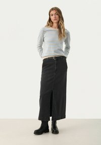 Stribet sweater i lyseblå og beige, parret med en sort denim maxi nederdel med en front slids og et bælte. Sorte ankelstøvler fuldender looket.