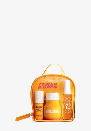 Trousse de voyage orange transparente contenant un baume à lèvres Sol de Janeiro Brazilian Kiss, une lotion Body Badalada et un flacon spray.